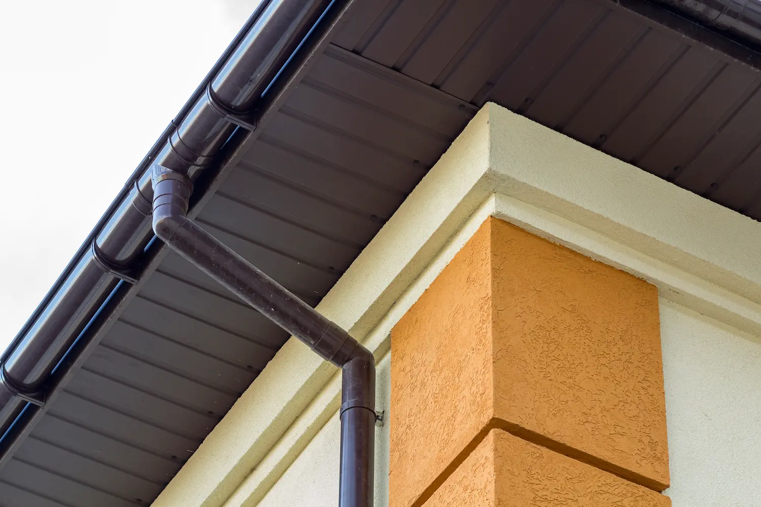 A close up of a gutter system on a roof by Bee Roofing And Exteriors
