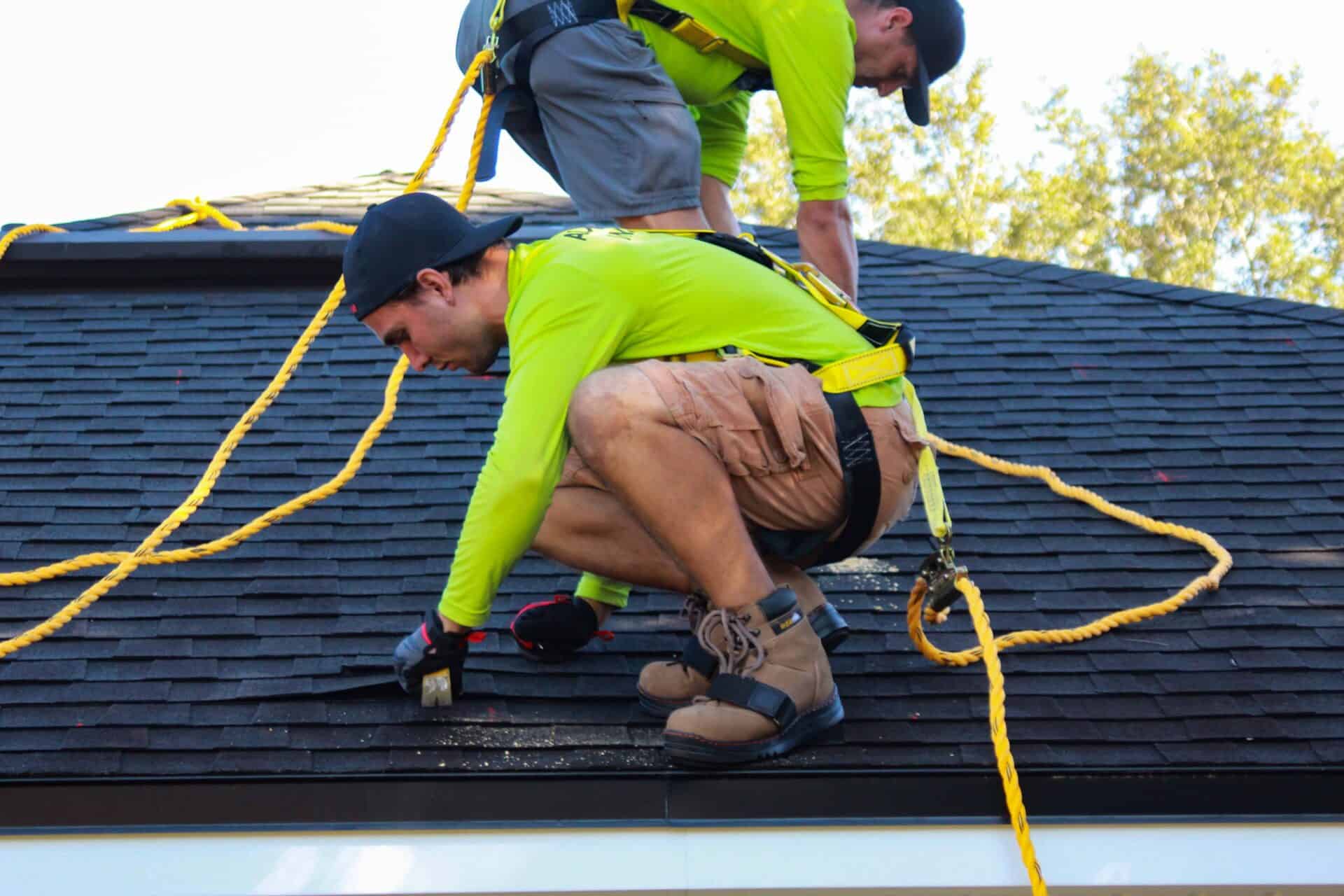 Two men from Bee Roofing And Exteriors removing an old roof.