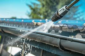pressure washer blasting water to a curved gutter
