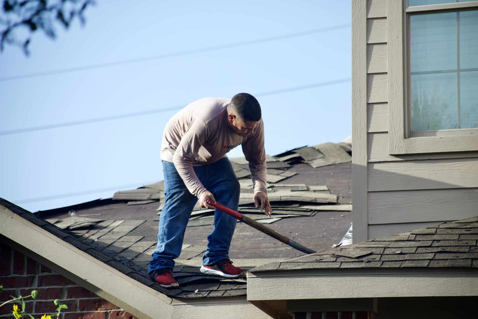A Bee Roofing And Exteriors worker removing the old roof.